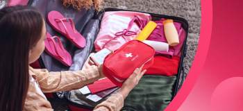 An international student adds a first aid kit to their suitcase.